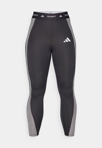 Sorte sports leggings med grå sidepaneler, med en Techfit midje og et adidas-logo på venstre lår. Glatt, elastisk stoff.
