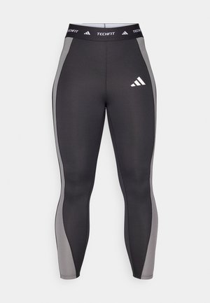 Leggings sportivi neri con pannelli laterali grigi, dotati di una cintura Techfit e di un logo adidas sulla coscia sinistra. Tessuto liscio e elasticizzato.