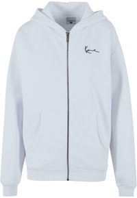Light blue zip-up hoodie made of soft fabric, featuring a front zipper, two side pockets, and a small black embroidered logo on the chest.