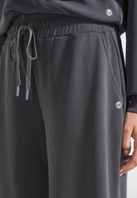 Dunkelgraue Sweatpants mit einem elastischen Bund und Kordelzug, ausgestattet mit seitlichen Taschen und einem kleinen Logodetail auf der Vorderseite.