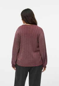 Bordo rebrasti pulover s dugim rukavima i suptilnim sjajem. Ima okrugli izrez i ležeran kroj, izrađen od mekanog, teksturiranog materijala.
