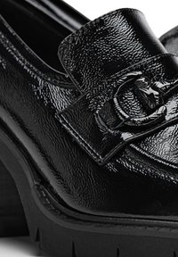 Schwarze Lacklederloafer mit glänzender Oberfläche, ausgestattet mit einer dekorativen Schnalle und einer dicken, strukturierten Plattformsohle.