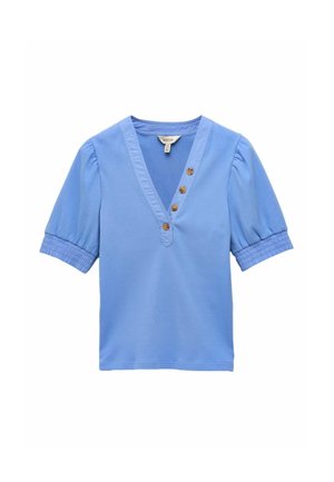 Camicetta azzurro chiaro con scollo a V e maniche corte a sbuffo, caratterizzata da quattro bottoni marroni lungo il colletto e una texture a coste.