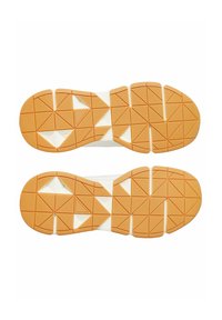 Gumowe podeszwy butów z fakturowanym pomarańczowym wzorem w kształcie trójkątów, obramowanym na biało. Fakturowana powierzchnia zapewniająca przyczepność.