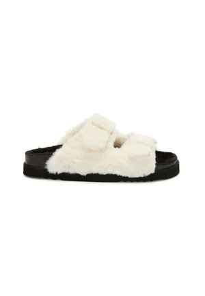 Vita fluffiga slidesandaler i vitt med två justerbara remmar, svart sula och en mjuk, texturerad yta. Platt design för komfort.