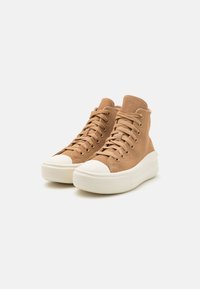 Hoogtop sneakers van tan suède met een witte rubberen neurol en een gestructureerde zool. Beschikt over traditionele veters en een gewatteerde kraag.