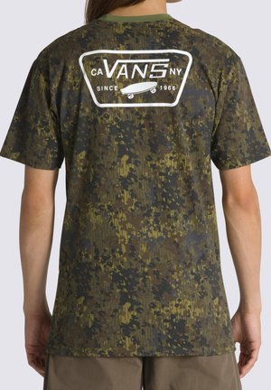 Person iført en Vans T-shirt med camouflageprint og hvidt skateboardlogo samt teksten "CA VANS NY Since 1966" på ryggen.