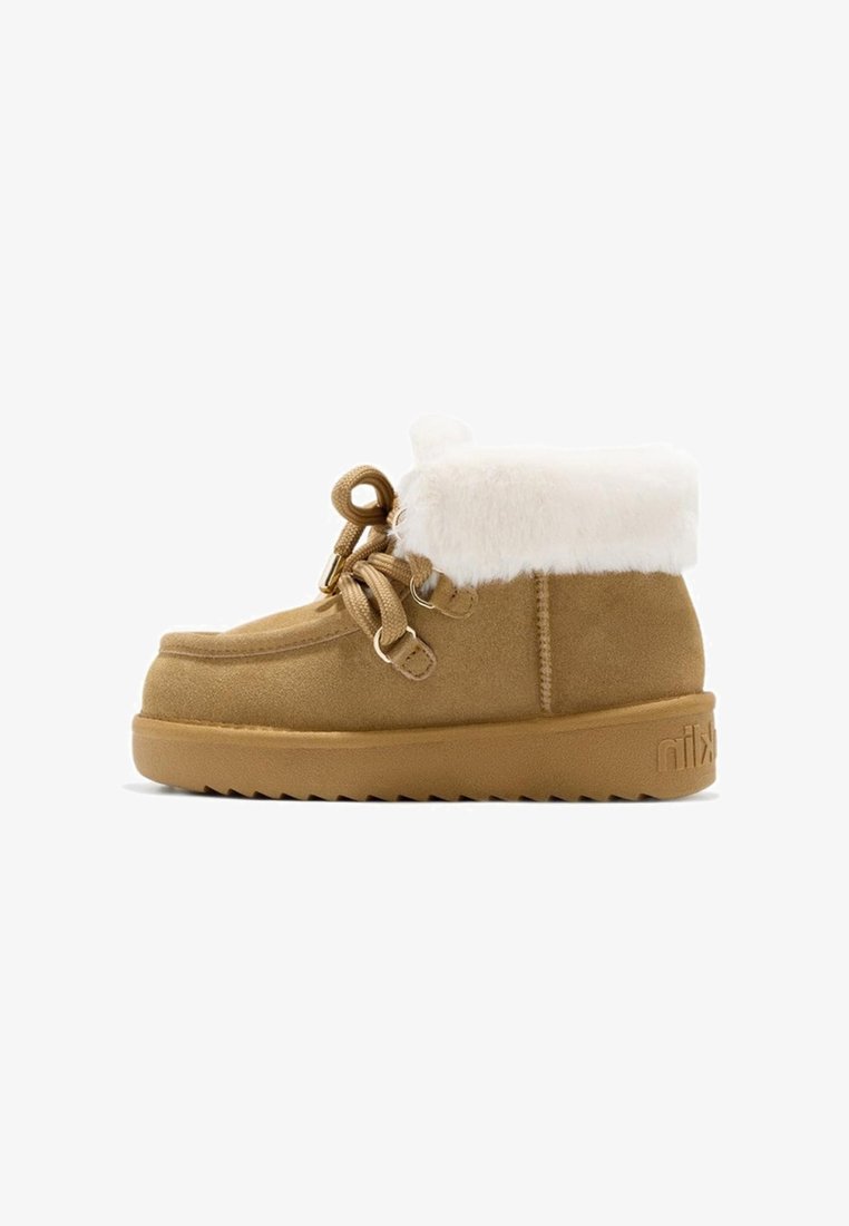 Botín de ante marrón con puño de pelo sintético blanco, punta redonda, cordones decorativos y suela de goma texturizada con patrón de zigzag.