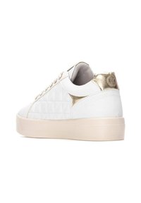 Sneakers bianchi trapuntati con un accento dorato sul tallone, caratterizzati da una punta arrotondata e una suola in gomma spessa e texturizzata.