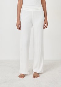 Pantalones blancos de pierna ancha, acanalados, con una textura suave y una cinturilla ajustada. El dobladillo está ligeramente deshilachado, lo que añade un detalle relajado.