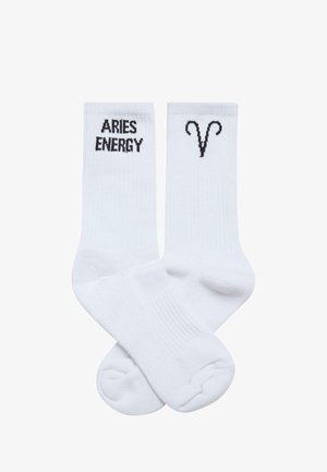 Baltas kokvilnas maisījuma zeķes ar melnu tekstu "ARIES ENERGY" no vienas puses un melnu Auna simbolu no otras. Rievota tekstūra augšpusē.
