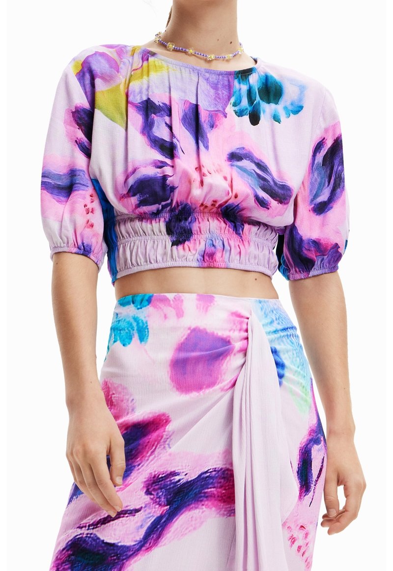 Barevná zkrácená blůza s nabíranými rukávy, zdobená květinovým vzorem v růžové, fialové, žluté a modré barvě. Lehce průsvitná látka se smocked pasem.