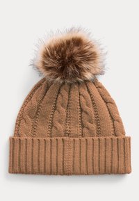 Barna kötött sapka fonott mintával, bordázott mandzsettával és egy nagy műszőrme pomponnal a tetején, puha textúrával és lekerekített alakzatú.