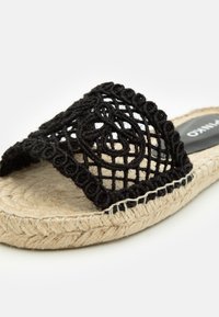 Černé krajkové klouzavé sandály se tkaným svrškem s kulatými vzory a přirozenou jutovou podrážkou. S akcentem černého prošívaného okraje.