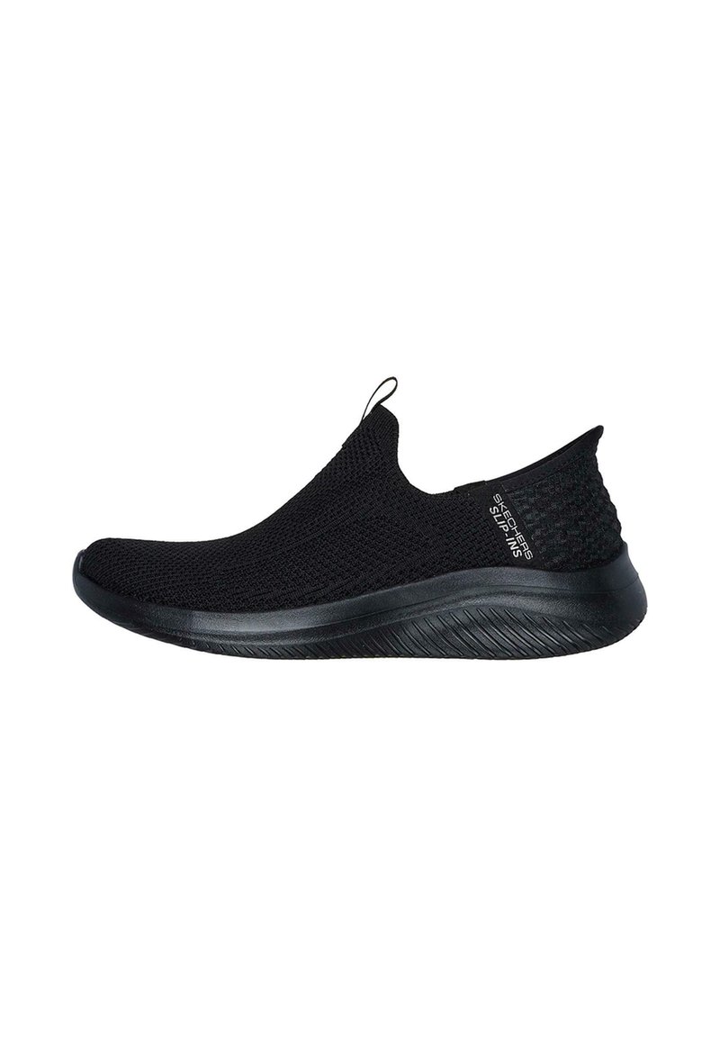 Zapatilla deportiva negra sin cordones con textura de punto, parte superior flexible y suela curva. Cuenta con una tira de sujeción y un diseño minimalista en la marca.