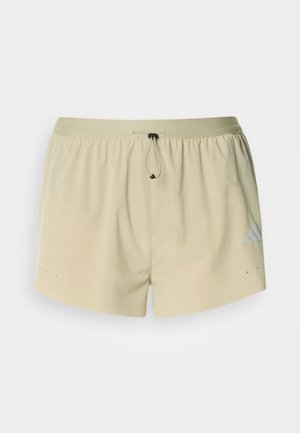 Μπεζ αθλητικό σορτς με ελαστική μέση, κορδόνι και πλαϊνές τσέπες· διαθέτει ένα μικρό λογότυπο στην αριστερή πλευρά και λεία υφή.