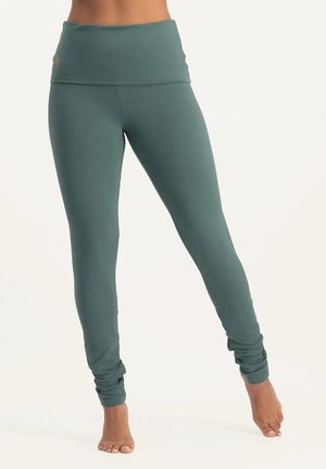 Hochgeschnittene, türkisfarbene Leggings aus dehnbarem Stoff. Mit einem umschlagbaren Bund und Raffung an den Knöcheln. Glatte Textur.