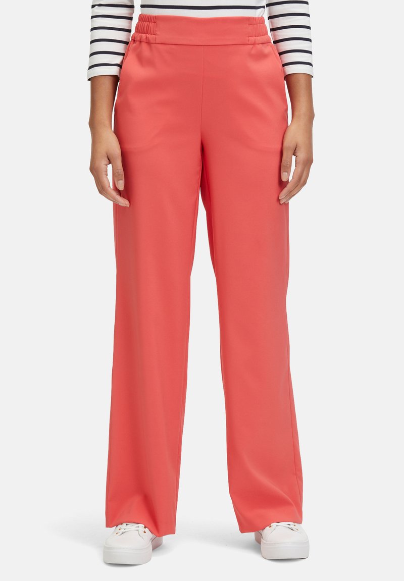 Coral wide-leg pants with an elastic waistband, made of smooth fabric, worn with a striped long-sleeve top and white sneakers.