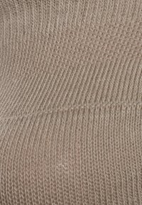 Tessuto lavorato a maglia beige con un motivo a costine testurizzato; presenta sottili linee verticali e orizzontali. Morbida texture e lucentezza sottile.