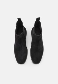 Schwarze Wildleder-Stiefeletten mit elegantem Design, runder Zehenpartie, elastischen seitlichen Einsätzen und Zuglaschen für einen einfachen Einstieg. Flache Gummisohlen.