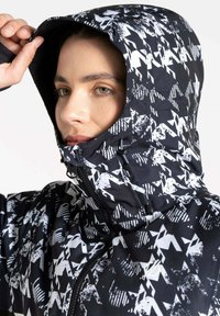Schwarz-weiße gemusterte Kapuzenjacke mit Reißverschluss, strukturiertem Stoff und verstellbarer Kapuze. Mit stilisierten grafischen Designs.