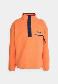 Sudadera de felpa naranja con tapeta de botones a presión en azul marino y bolsillo con cremallera en el pecho, que presenta un logo de la marca Columbia en la parte frontal.