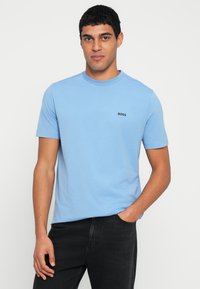 Ανοιχτό μπλε μπλουζάκι από μαλακό βαμβάκι, με κοντά μανίκια και στρογγυλή λαιμόκοψη, με μικρό μαύρο λογότυπο "BOSS" στην αριστερή πλευρά του στήθους.