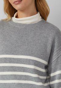 Grauer Pullover mit weißen horizontalen Streifen, gerippter Rundhalsausschnitt, strukturiertes Strickmuster und detaillierte Akzente an den Ärmelkanten.