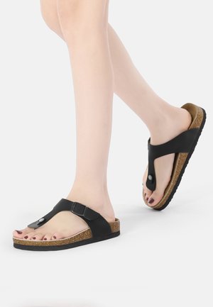 Black vegan leather sandals with a thong design, buckle accent, and cork-textured footbed. Rubber outsole offers grip and durability.