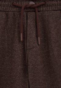 Bruna texturerade sweatpants med ett vävt mönster, som har en dragsko i midjan och plastögla. Sidofickdetalj inkluderad.