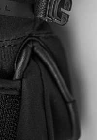 Cinturino in tessuto nero con superficie testurizzata e cuciture visibili, intrecciato con una sezione in pelle liscia e una chiusura in plastica.