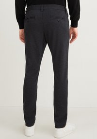 Tmavě šedé zúžené kalhoty z texturované tkaniny s zadními kapsami, se středně vysokým pasem a bočními šikmými kapsami. V kombinaci s bílými teniskami.