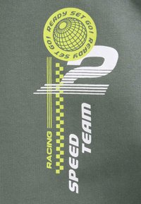 Grön tyg med djärva vita och livliga gula grafiska texter och mönster, inklusive "RACING", "SPEED TEAM" och en globdesign.