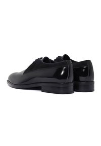 Chaussures habillées en cuir noir avec une finition brillante, accents en daim et un petit talon empilé. Bout rond et design de laçage simple.