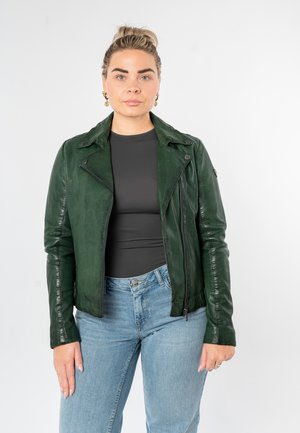 Grüne Leder-Bikerjacke mit tailliertem Schnitt, Reißverschluss und Schulterklappen. Getragen über einem schwarzen Oberteil und kombiniert mit hellblauen Jeans.