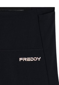 Leggings sportivi neri realizzati in materiale elastico, con una leggera lucentezza e un piccolo logo metallico "FREDDY" sul lato sinistro in basso.