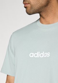 Hele sinine puuvillane t-särk, millel on valge "adidas" logo rinnal. Lühikesed varrukad ja ümara kaelusega disain. Pehme tekstuur.