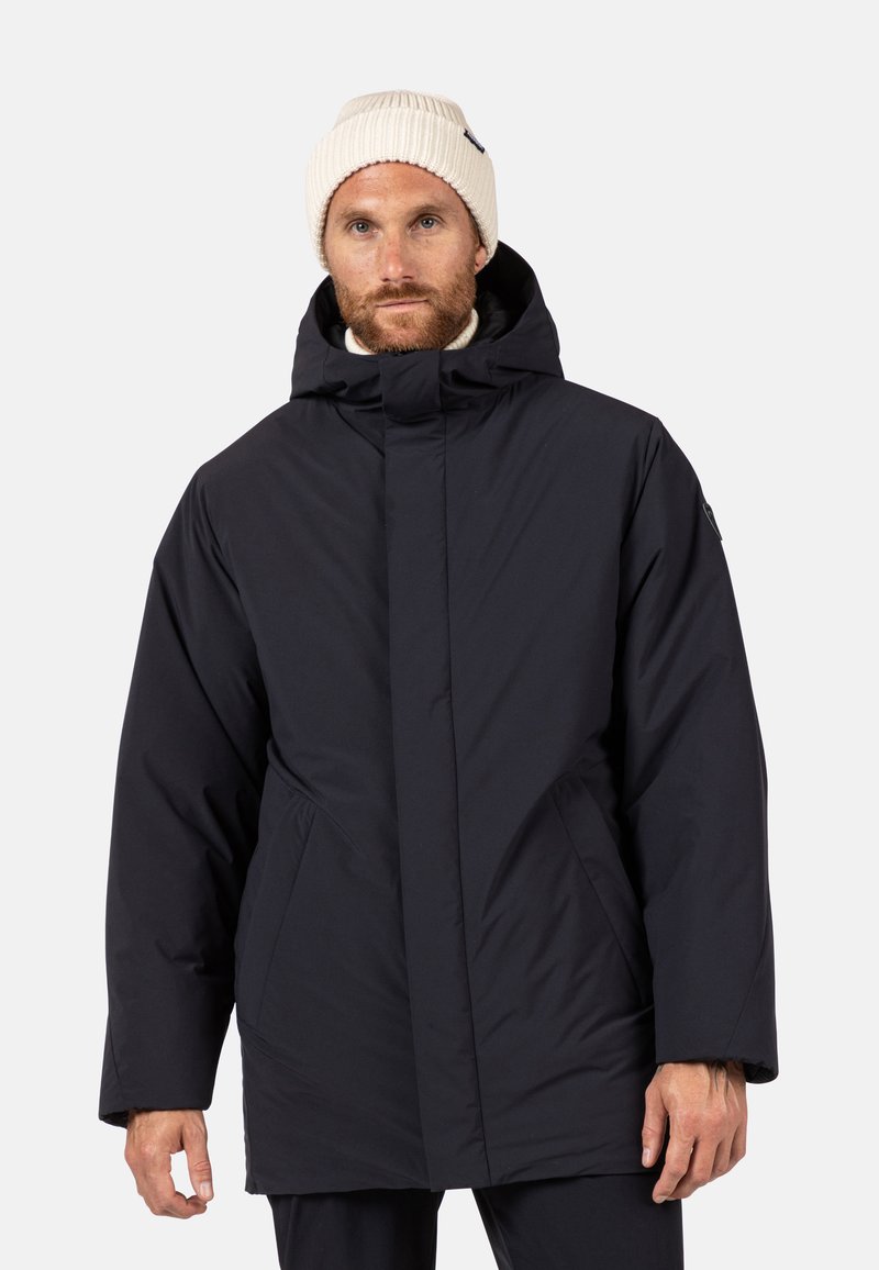 Chaqueta aislante azul marino con cuello alto, bolsillos frontales y capucha. Fabricada con tejido suave de acabado mate, presenta un corte relajado.