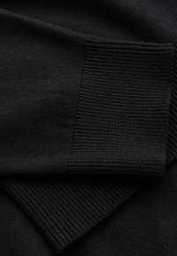 Czarna dzianinowa sweter z ribbowymi mankietami i gładką fakturą, z zbliżeniem pokazującym szczegóły splotu i spójność koloru.