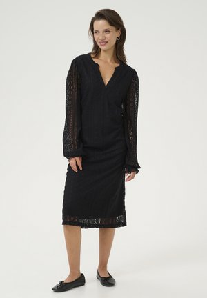 Black lace dress with long sleeves and a deep V-neck. Fitted silhouette, below-the-knee length, featuring intricate lace patterns.