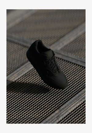Tenis de culoare neagră cu un superior din piele netedă, vârf rotund și șireturi plate. Dispune de o talpă texturată și un branding subtil pe limbă.