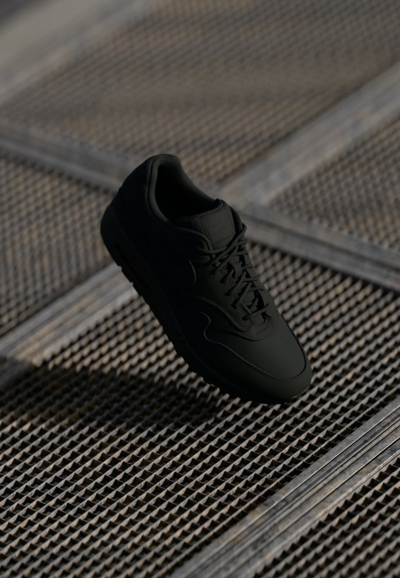 Sorte sneakers med en glatt læroverdel, rund tå og flate lisser. Har en teksturert såle og subtil merkingen på tungen.