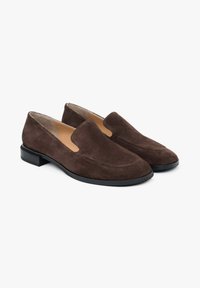 Brown suede slip-on shoes with a low black heel, featuring a smooth texture and minimal stitching detail along the upper.