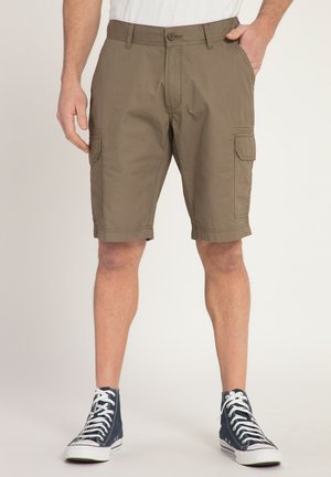 Shorts cargo kaki avec une coupe plate, des poches latérales et une fermeture à bouton. Le tissu est en coton léger. Portés avec des baskets montantes bleu marine.