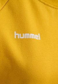 Gul bomull t-shirt med en vit "hummel" logotyp, med en slät textur och rundad halsringning.