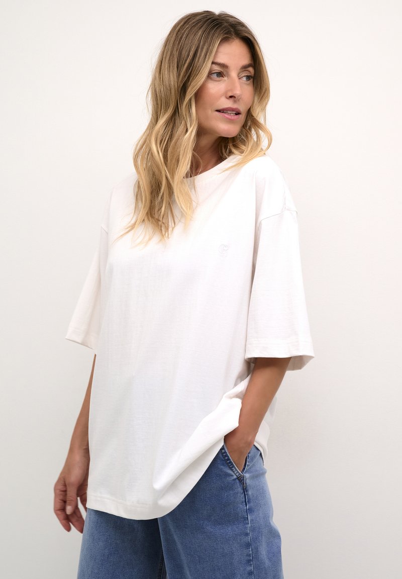T-shirt bianco in cotone con una vestibilità ampia e maniche corte, caratterizzato da un collo rotondo e un sottile dettaglio del logo sul petto.