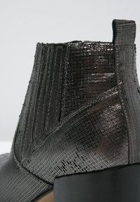 Schwarze Leder-Ankle-Boots mit strukturiertem Design, rechteckigem Absatz, elastischer Seitenpartie und dezentem Glanz mit horizontalen Rillen.