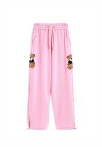 Pantalones de chándal rosa con cordón en la cintura, que cuentan con dos apliques de osito en los bolsillos frontales y puños con cremallera en los tobillos. Textura de tela suave.