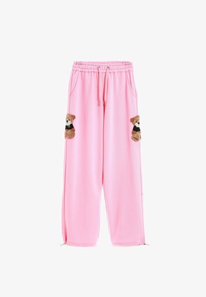 Pantalones de chándal rosa con cordón en la cintura, que cuentan con dos apliques de osito en los bolsillos frontales y puños con cremallera en los tobillos. Textura de tela suave.