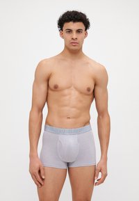 Grå bomull boxertruser med en glatt tekstur og en bred elastisk midjebånd som har teksten "OUR UNDER" i lyseblå.